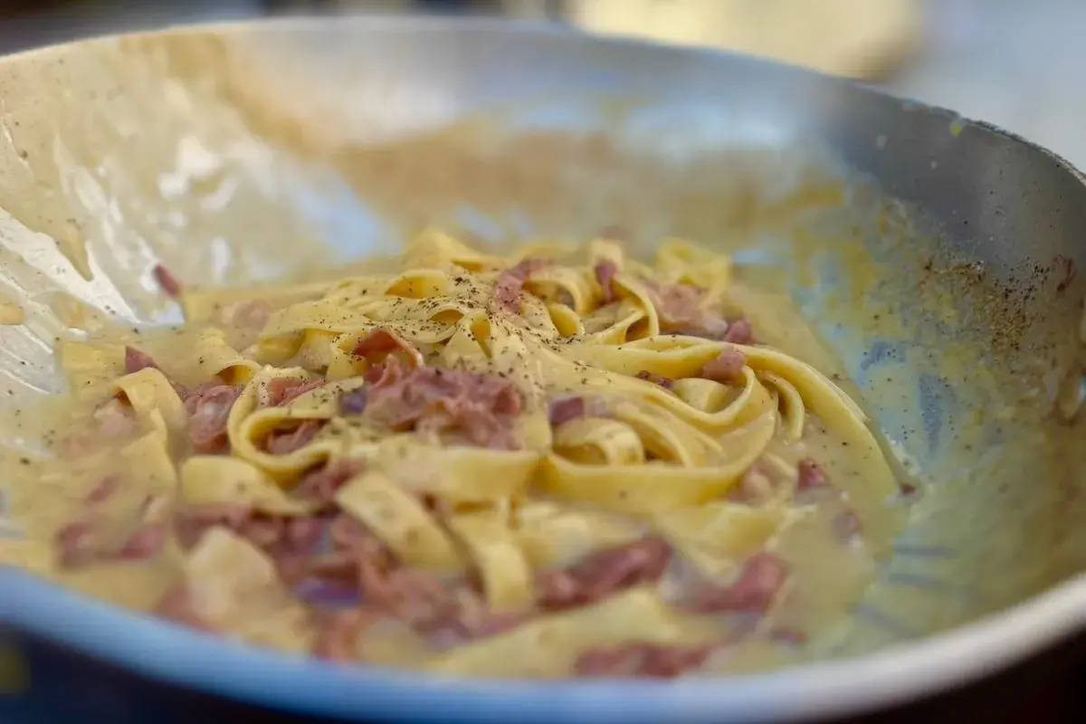 Fettuccine alla papalina crémeux et poivré, servi dans une poêle.