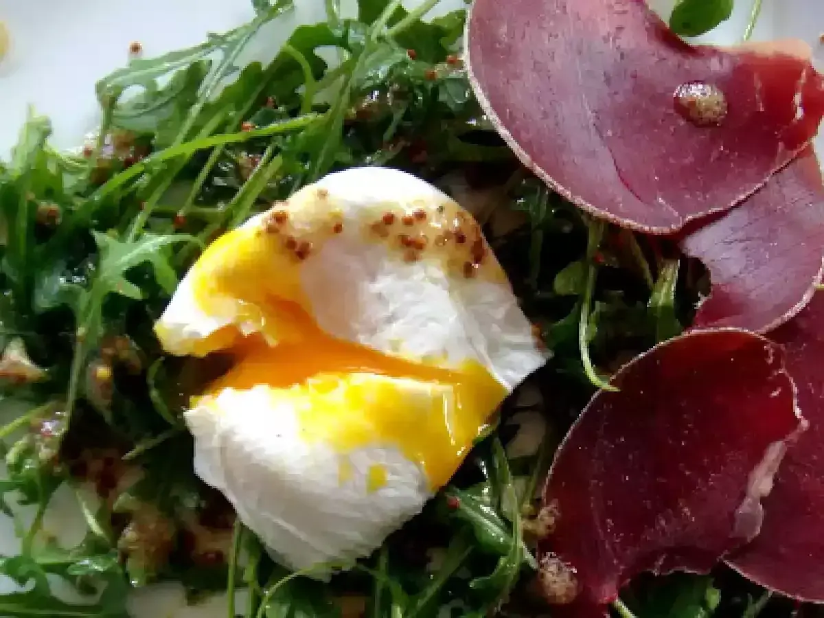 Salade lyonnaise avec œuf poché coulant, roquette et fines tranches de viande séchée.