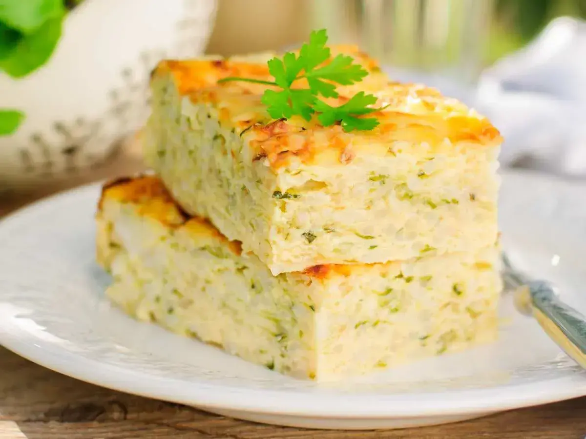 Deux parts de flan de courgettes facile, garnies de persil frais, sur une assiette blanche.