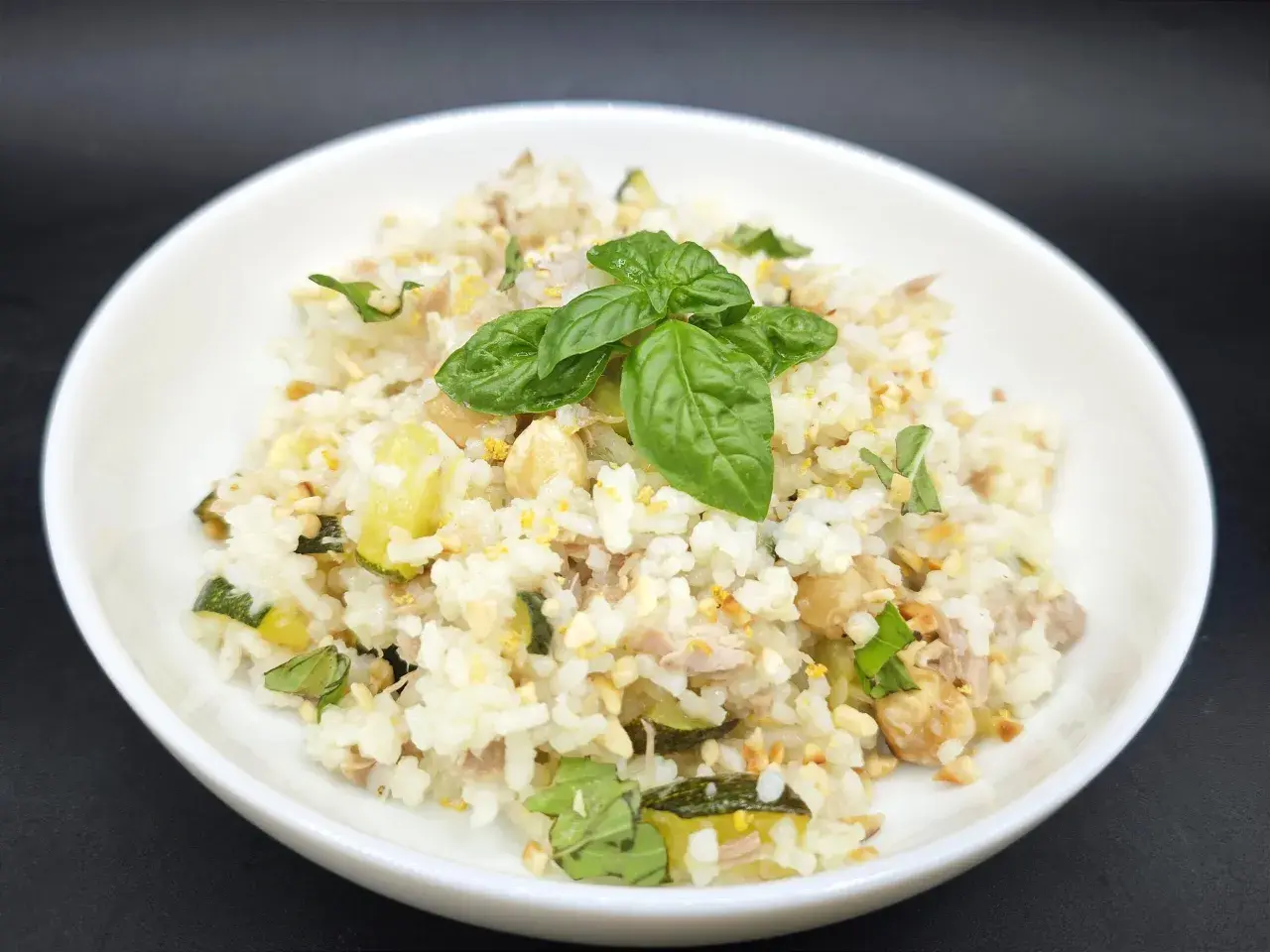 Un plat de riz aux courgettes et thon, garni de basilic frais. Une recette simple et savoureuse.