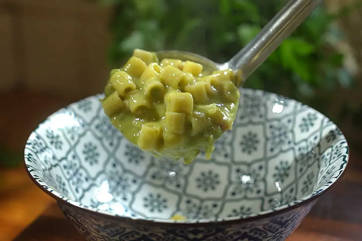 Une louche de pâtes ditalini dans une sauce crémeuse aux petits pois, parfaite pour une recette italienne simple et savoureuse.