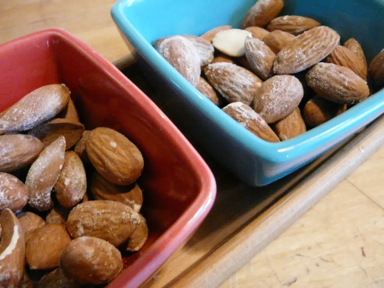 Deux bols, un rouge et un bleu, remplis d'amandes salées. Parfait pour un apéritif !