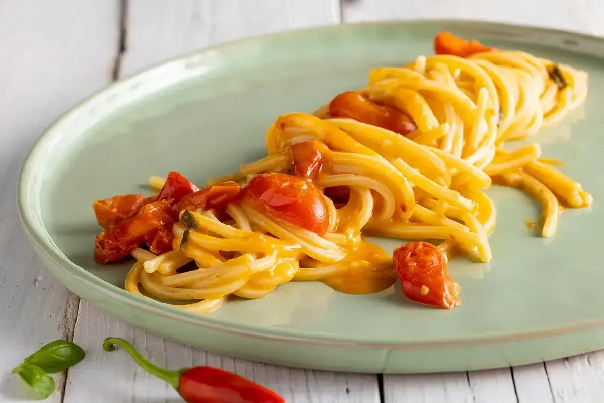 Un plat de scarpariello pasta, des spaghettis aux tomates cerises et au piment rouge, sur une assiette verte.
