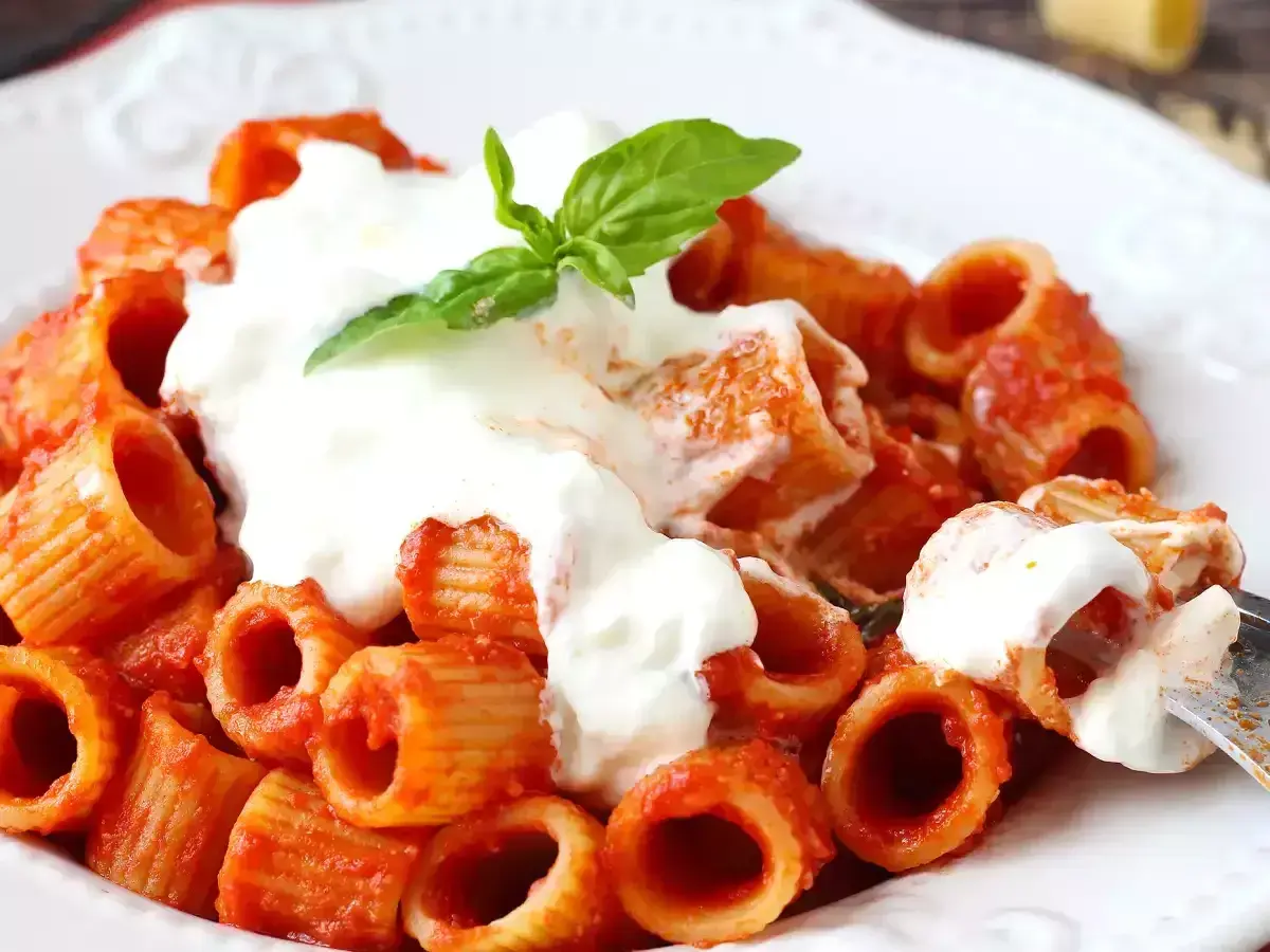 Pâtes rigatoni en sauce tomate, généreusement nappées de stracciatella crémeuse et garnies d'une feuille de basilic frais. Un délice !