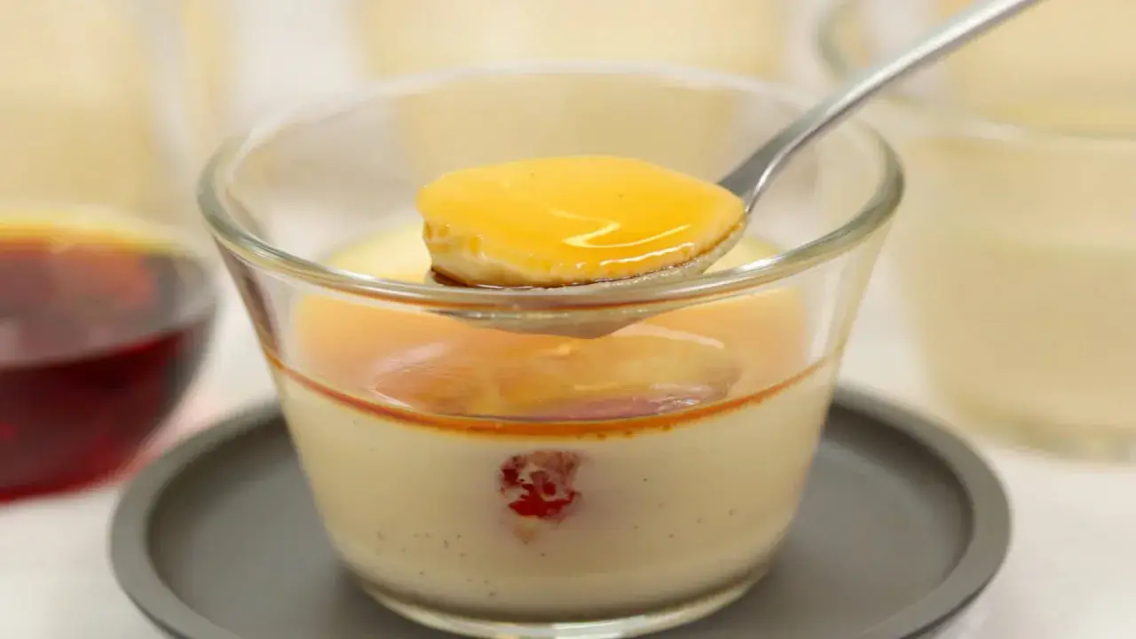 Cuillère de crème caramel onctueuse, nappée de sauce dorée, dans un verre. Un délice à savourer.