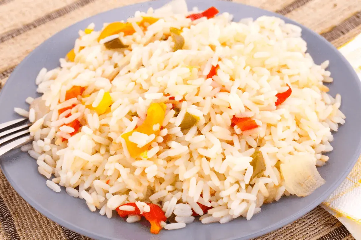 Une assiette de riz créole coloré avec des morceaux de poivrons rouges et jaunes.