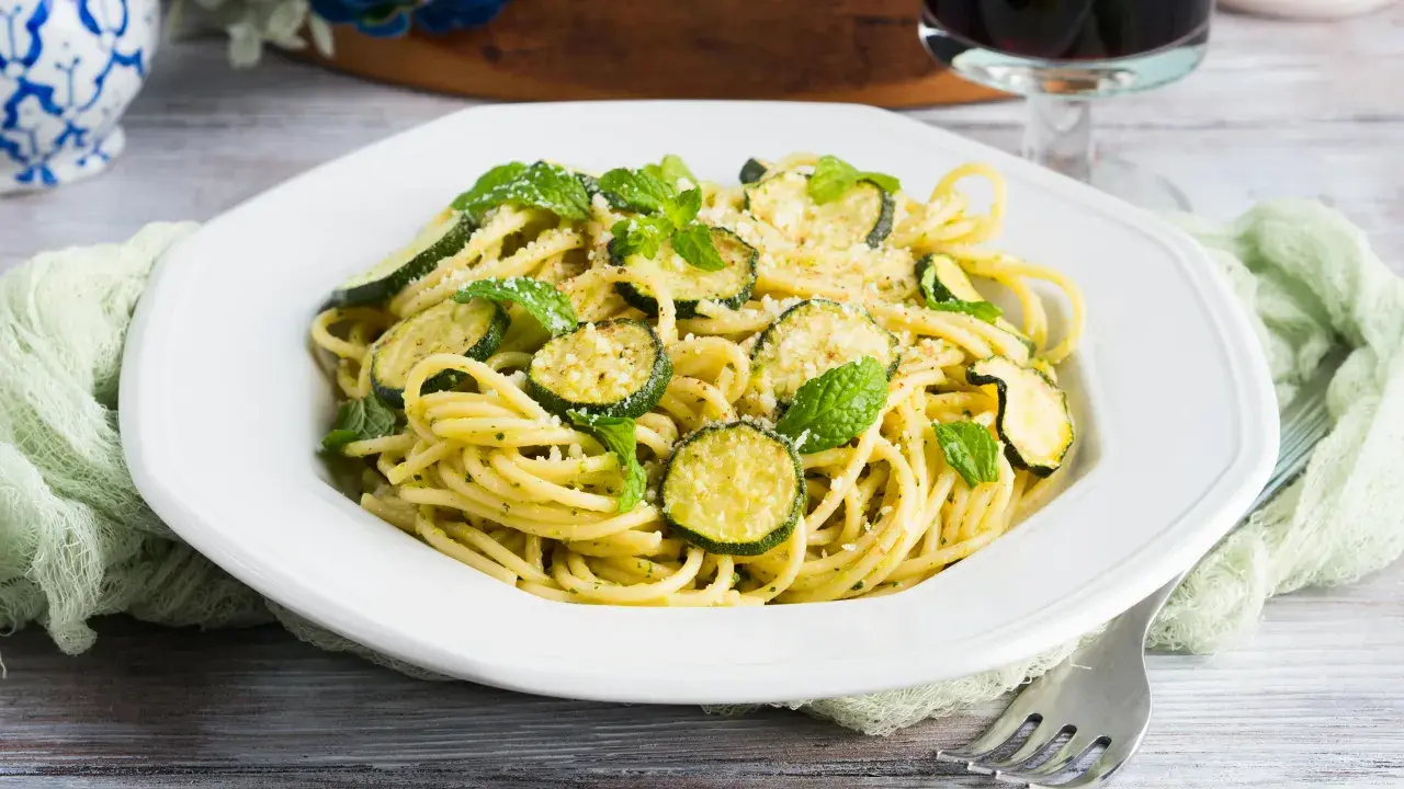 Spaghetti alla Nerano, un plat de pâtes crémeux aux courgettes et à la menthe fraîche, garni de parmesan râpé.