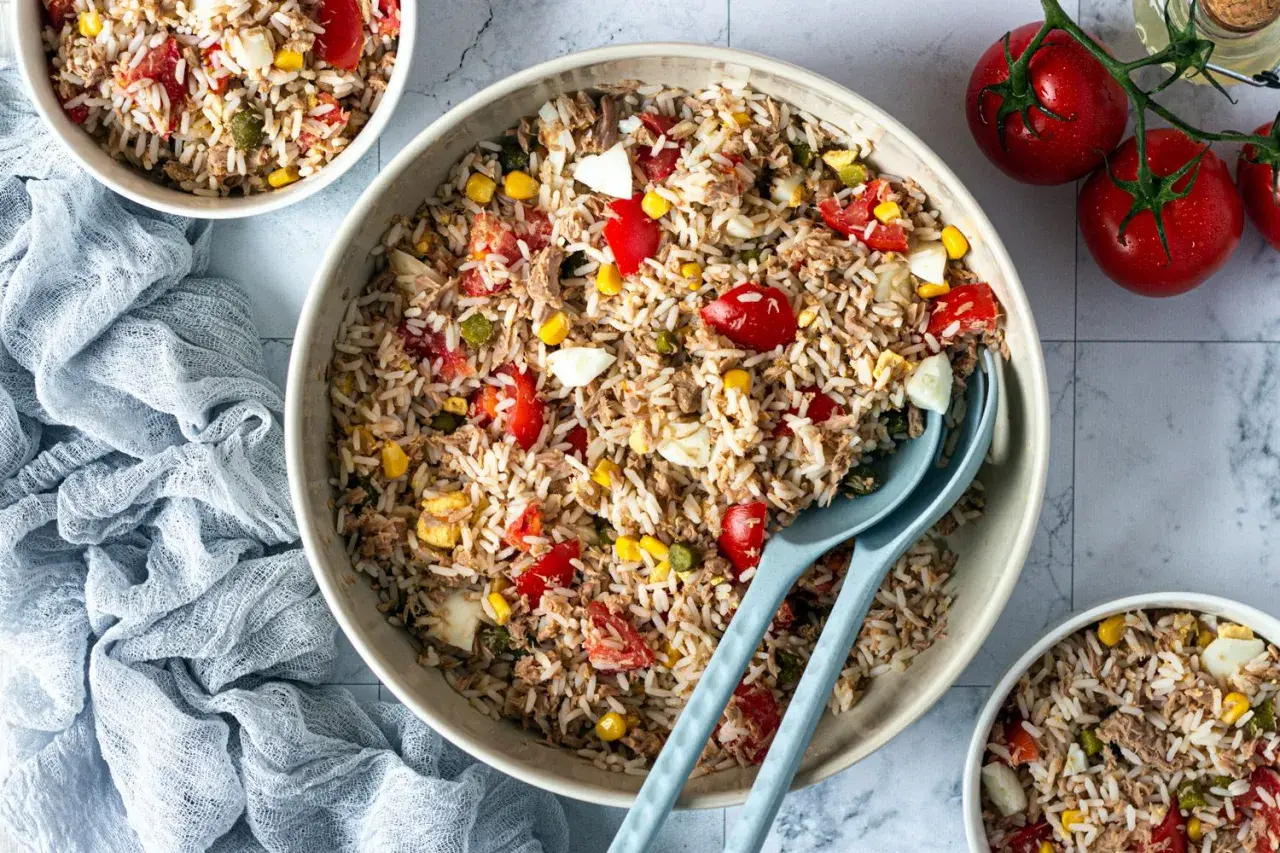 Une généreuse salade de riz italienne, garnie de thon, tomates, maïs et œufs durs, prête à être dégustée.