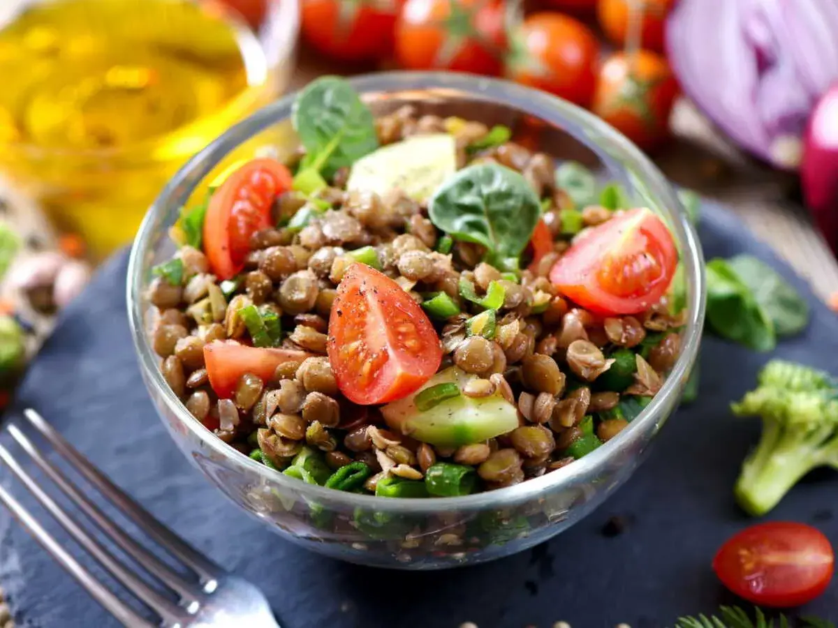 Salade de lentilles traditionnelle, fraîche et colorée, garnie de tomates cerises, concombre et oignons verts. Un délice sain.