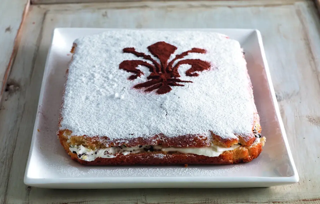 Schiacciata fiorentina, un g&acirc;teau rectangulaire saupoudr&eacute; de sucre glace, orn&eacute; d'un lys rouge.