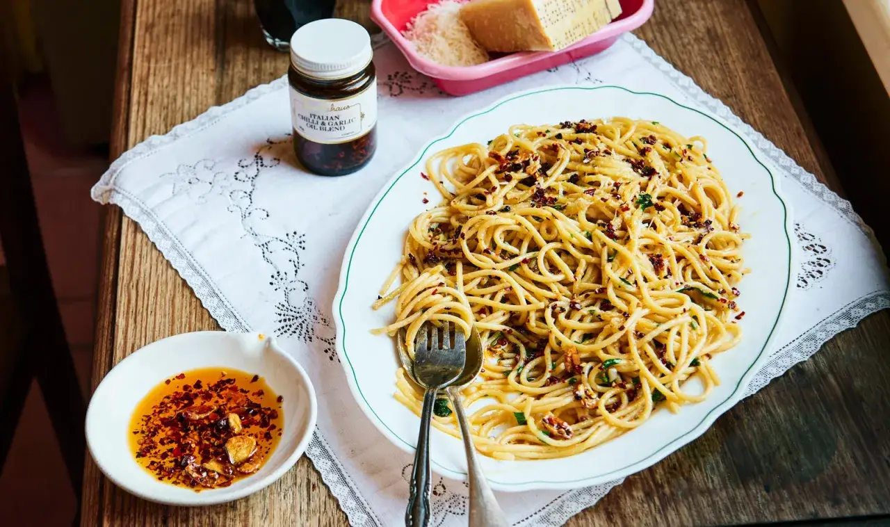 Un plat de spaghetti carrettiera, garni de flocons de piment et d'ail, servi avec une sauce piquante et du parmesan r&acirc;p&eacute;.