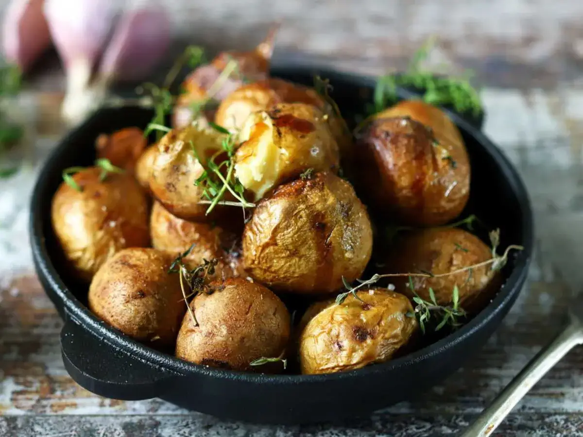 Pommes de terre grenaille dorées et croustillantes, juste sorties de l'airfryer, garnies de thym frais.