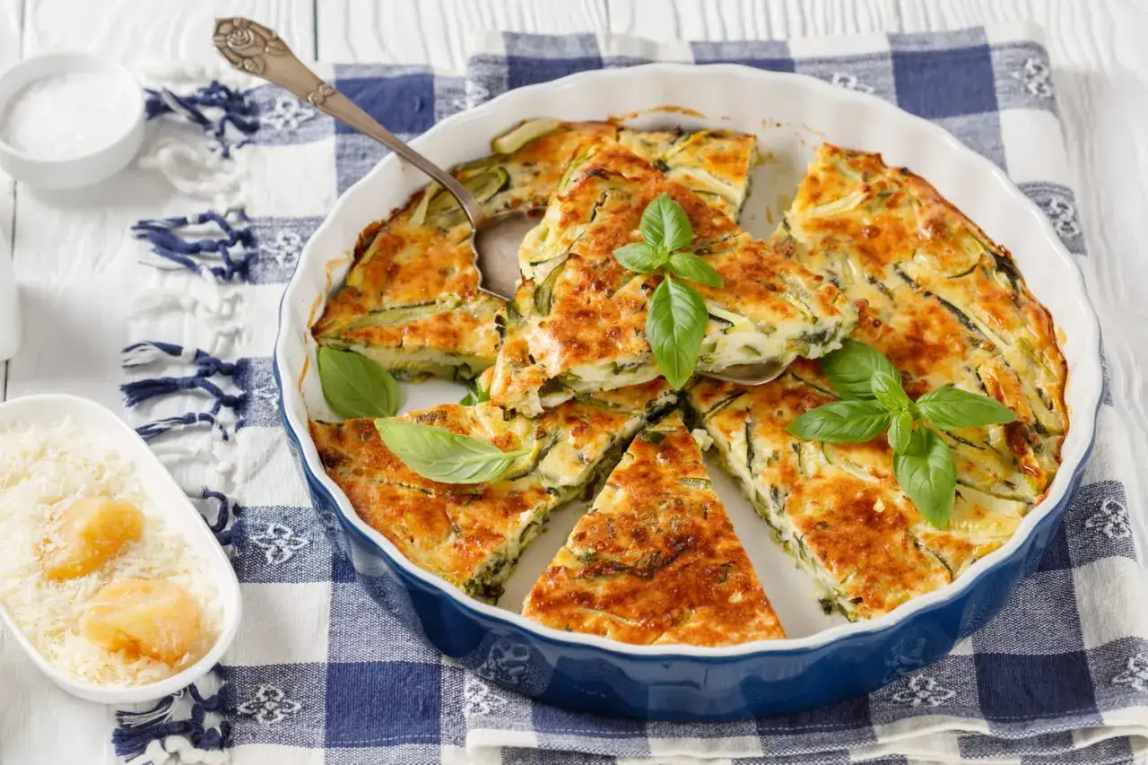 Une délicieuse scarpaccia de courgettes, dorée et garnie de basilic frais, prête à être dégustée.