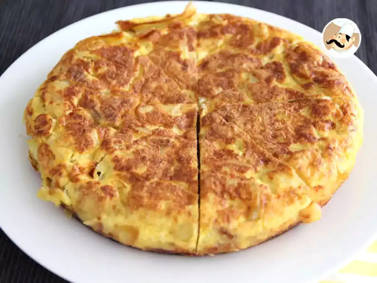 Une tortilla espagnole dor&eacute;e et app&eacute;tissante, coup&eacute;e en quartiers, sur une assiette blanche.