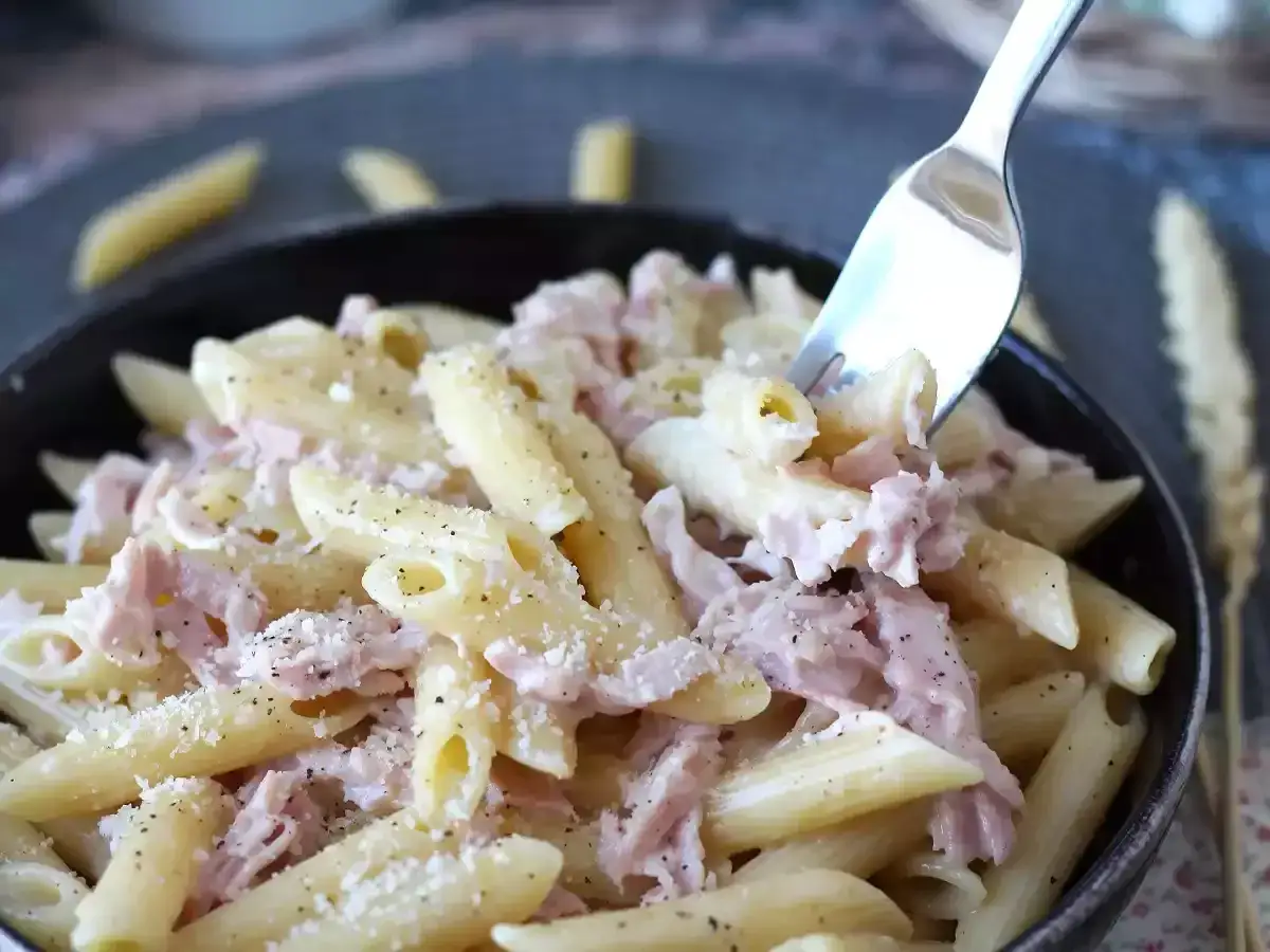 Une fourchette pr&eacute;l&egrave;ve des p&acirc;tes au jambon cr&eacute;meuses et saupoudr&eacute;es de parmesan. Un plat r&eacute;confortant pr&ecirc;t &agrave; &ecirc;tre d&eacute;gust&eacute;.