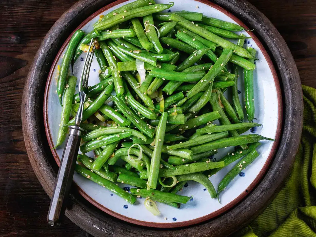 Assiette de haricots verts sautés, parsemés de graines de sésame. Un délice de haricot frit prêt à être dégusté.