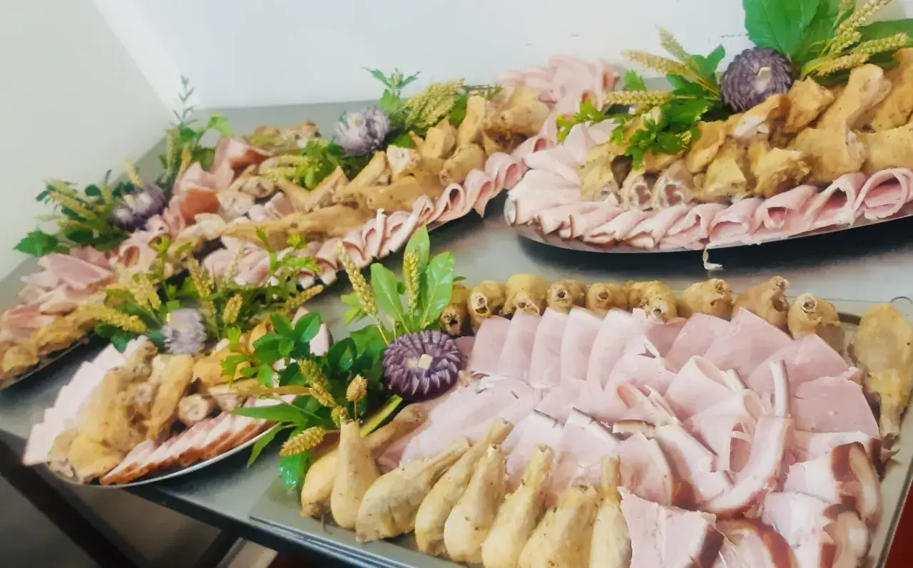 Plateaux garnis de jambon, de morceaux de poulet panés et de décorations végétales. Un délice pour les yeux et les papilles, parfait pour un buffet.