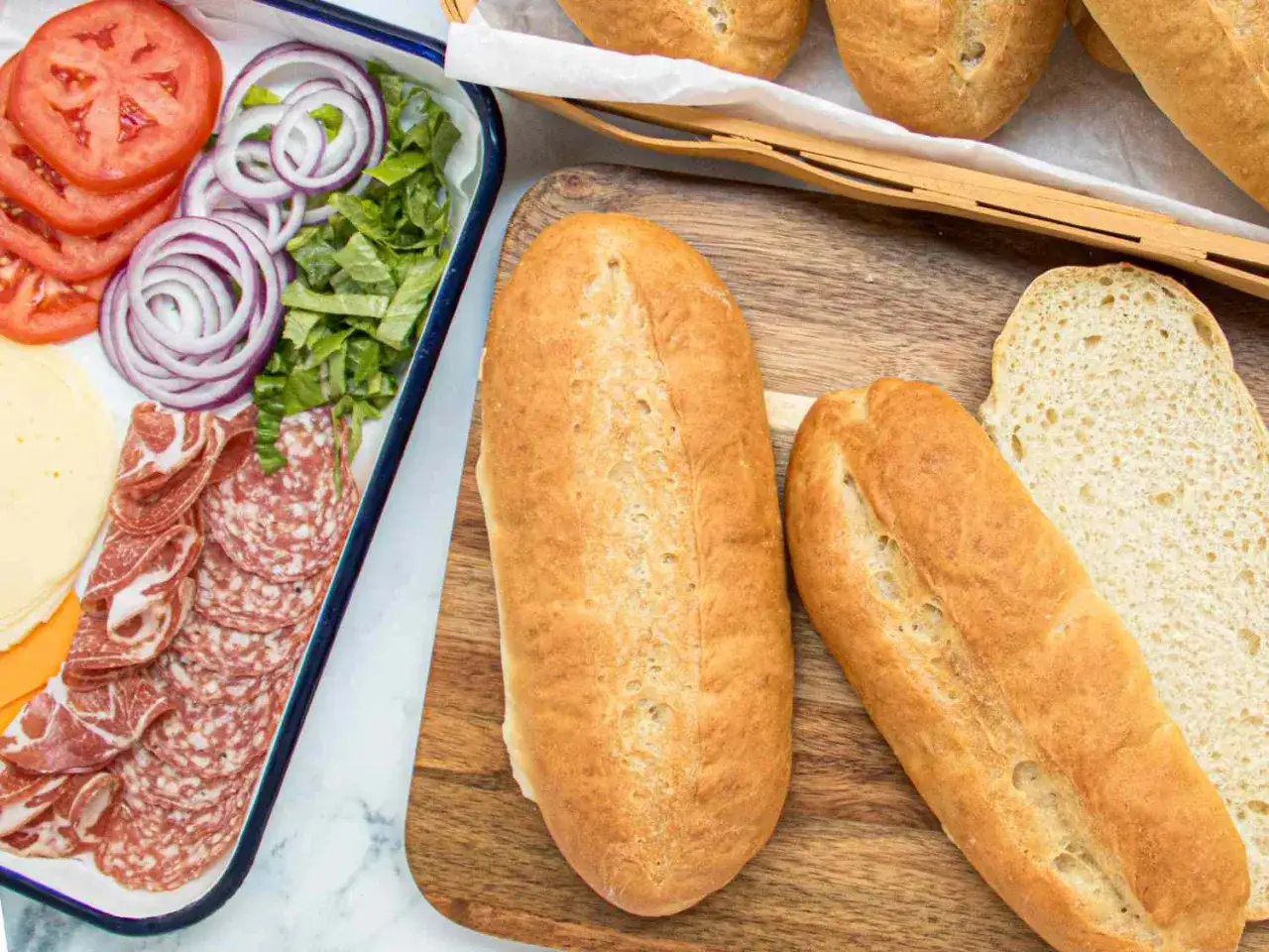 Préparation d'une tramezzini recette : pain, salami, fromage, tomates, oignons et laitue prêts à être assemblés.