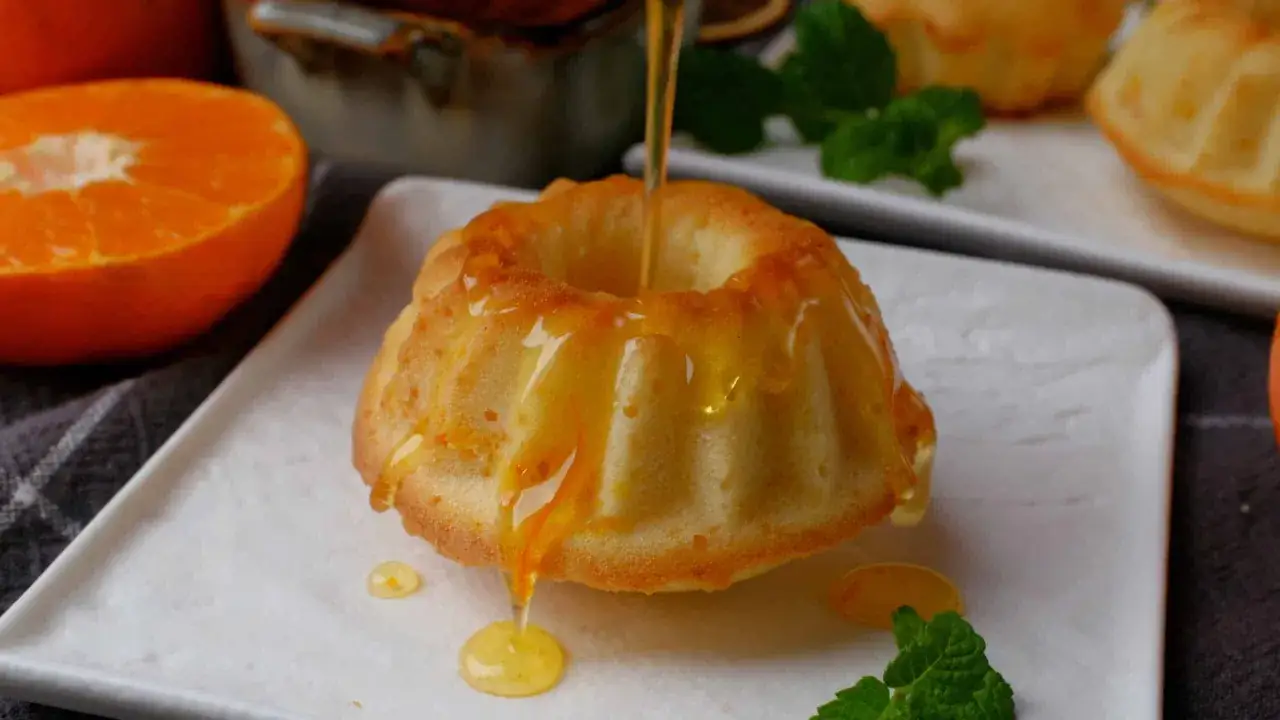Un délicieux gâteau mandarine est arrosé de miel doré, avec des quartiers d'orange et de la menthe fraîche en garniture.