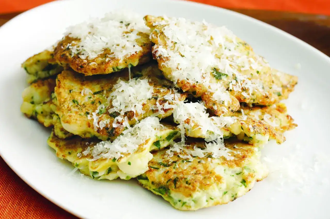 Beignets de choux-fleur italiens, dorés et garnis de parmesan râpé, sur une assiette blanche.