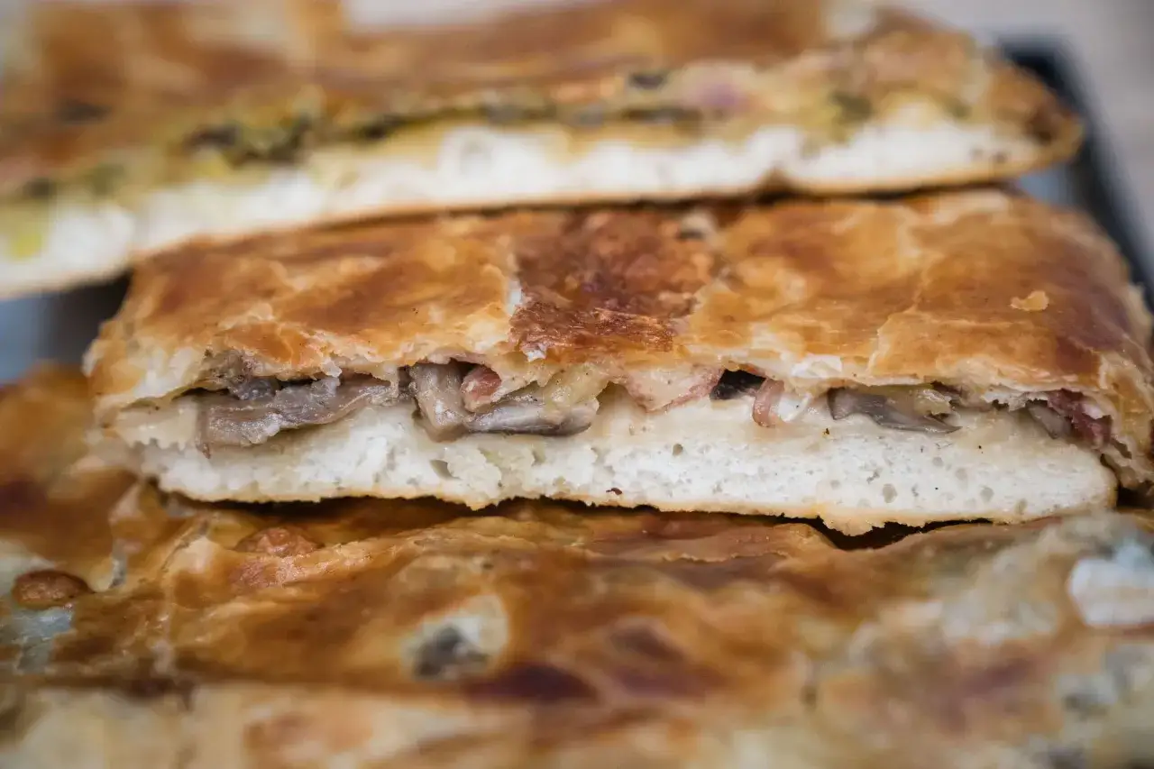 Une parigina napoletana dorée, garnie de champignons et de lardons, prête à être dégustée.