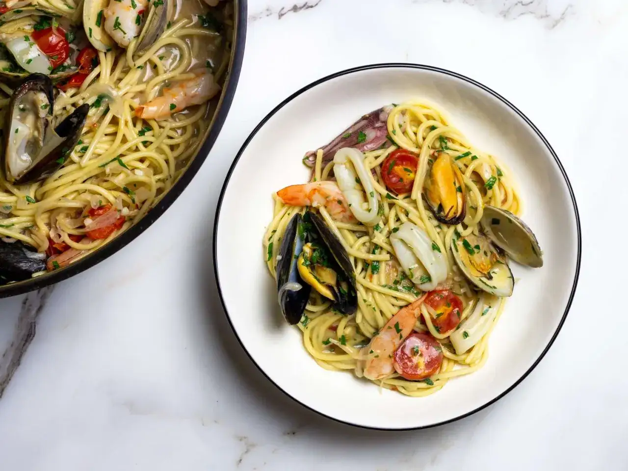 Un plat de spaghetti fruits de mer italienne, garni de crevettes, moules, calamars et tomates cerises, prêt à être dégusté.