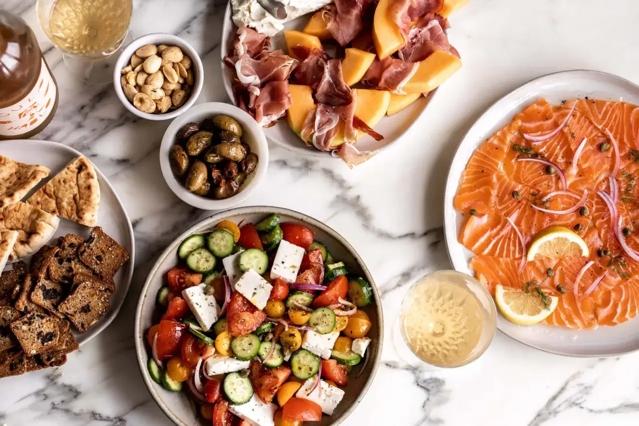 Idée apéro rapide sans cuisson : saumon fumé, salade grecque, melon prosciutto, olives, pain pita et crackers. Parfait pour un moment gourmand !