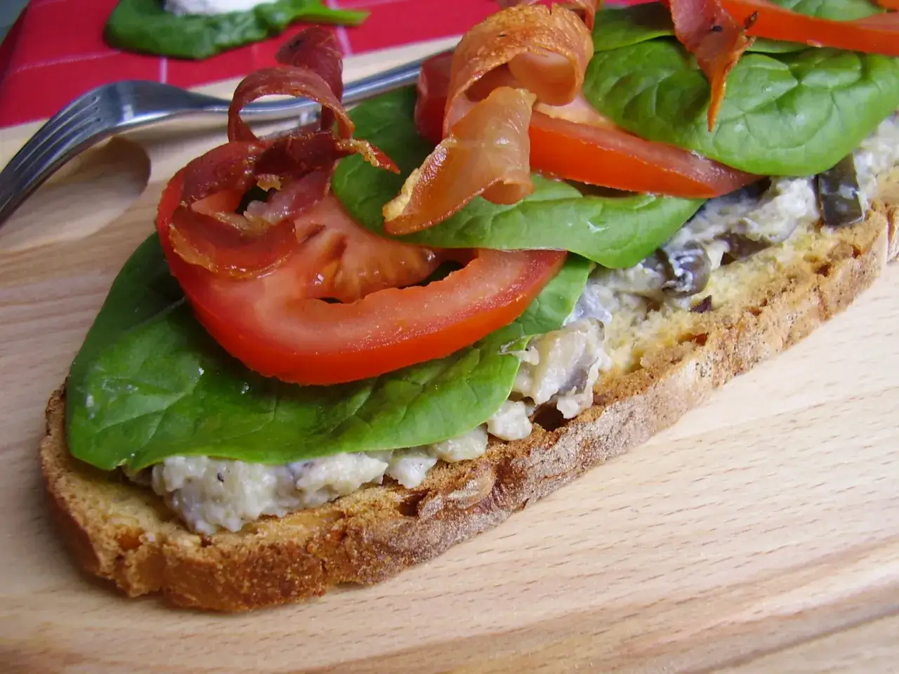 Tartine garnie de caviar d'aubergine, tomates, &eacute;pinards et fines tranches de viande s&eacute;ch&eacute;e.
