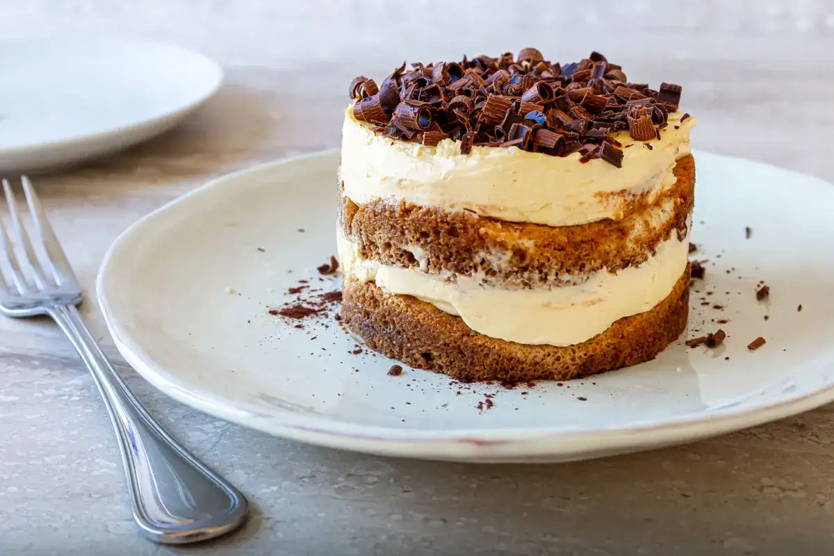 Un délicieux tiramisu gateau, empilé avec de la crème et garni de copeaux de chocolat, prêt à être dégusté avec une fourchette.
