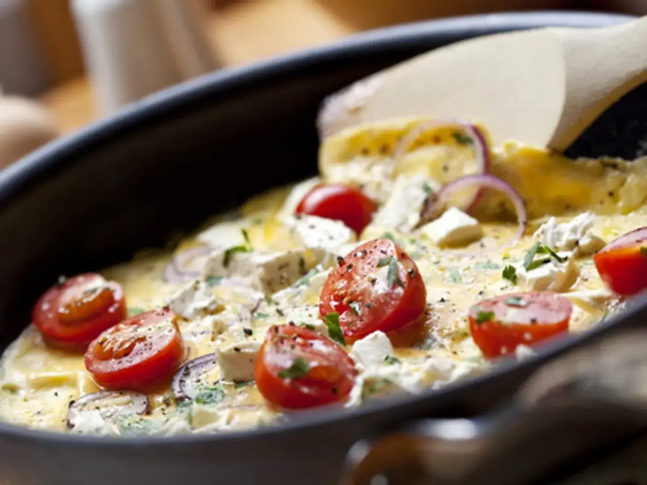 Une savoureuse omelette grecque avec tomates cerises, feta et oignons rouges, prête à être dégustée.