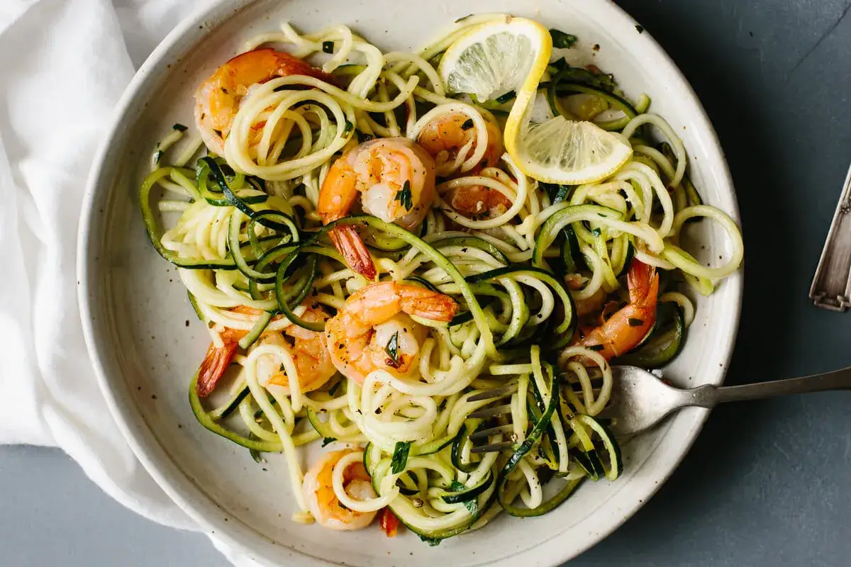 Délicieux linguine de courgettes avec crevettes et rondelles de citron. Un plat léger et savoureux.