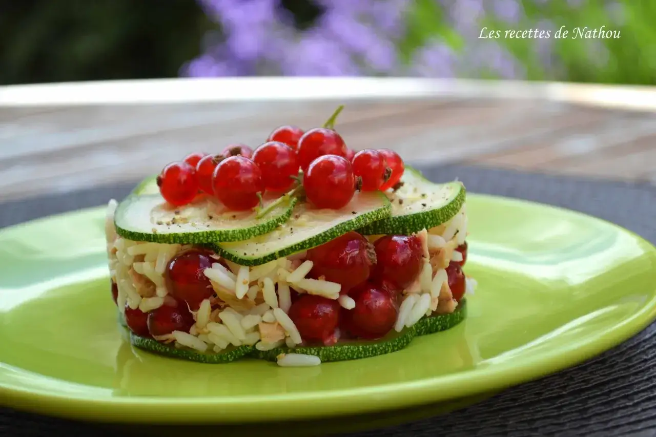 Délicieuse recette thon courgette, riz, garnie de groseilles et servie sur une assiette verte.