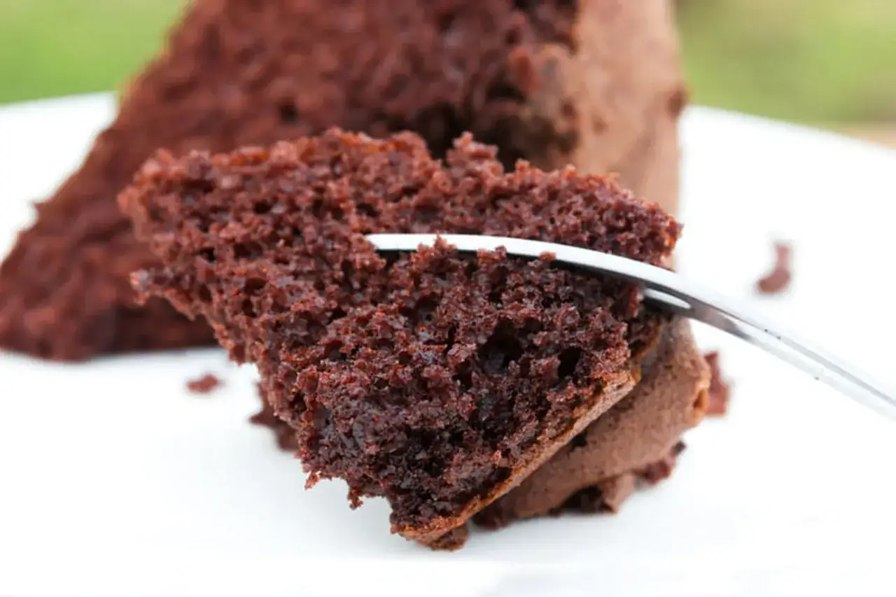 Une part de gâteau au chocolat moelleux, parfaite pour une recette facile. Une fourchette s'enfonce dans la texture aérée.