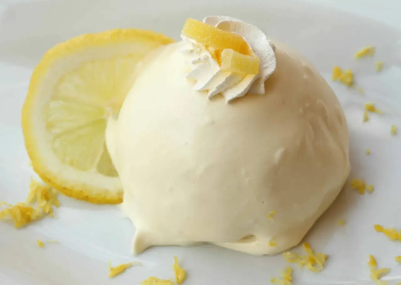 Une d&eacute;licieuse *delizia al limone* cr&eacute;meuse, garnie de chantilly et de zestes confits, accompagn&eacute;e d'une tranche de citron frais.
