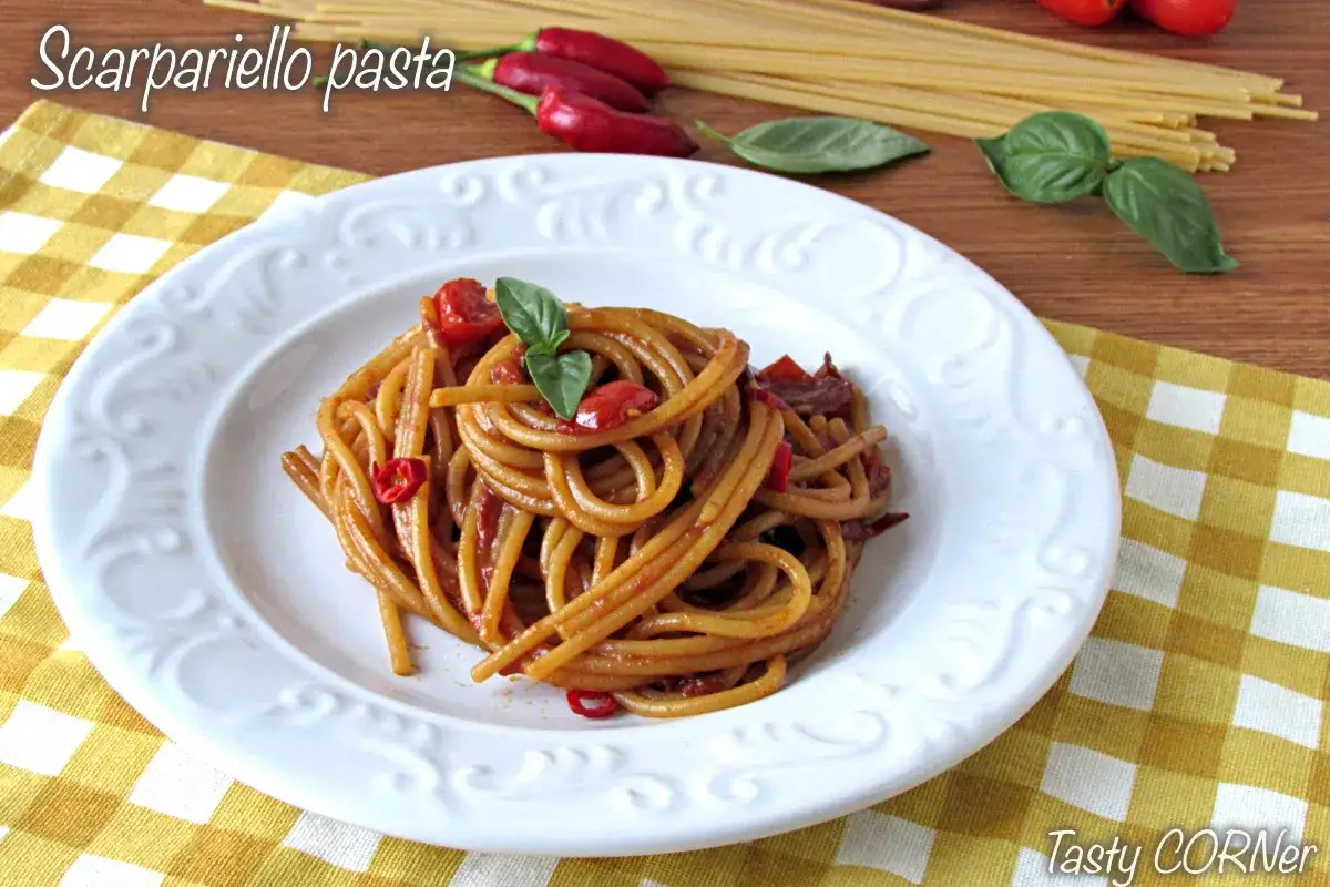 Assiette de scarpariello pasta, un plat de pâtes aux tomates et piments, garni de basilic frais.