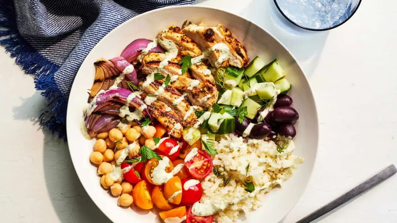 Une délicieuse salade composée avec poulet grillé, oignons rôtis, pois chiches, tomates, concombre, olives et riz, le tout arrosé d'une sauce crémeuse.