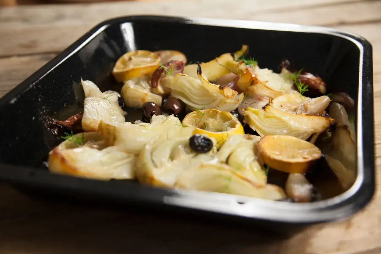 Un plat de fenouil rôti avec des citrons et des olives, prêt à être dégusté. Une délicieuse recette fenouil.