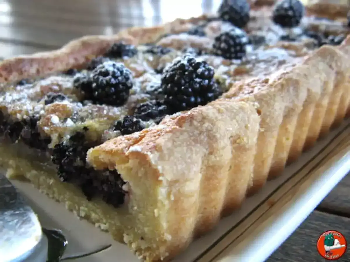 Tarte rectangulaire aux mûres, saupoudrée de sucre glace. Une délicieuse recette de tarte aux mûres, parfaite pour l'été.