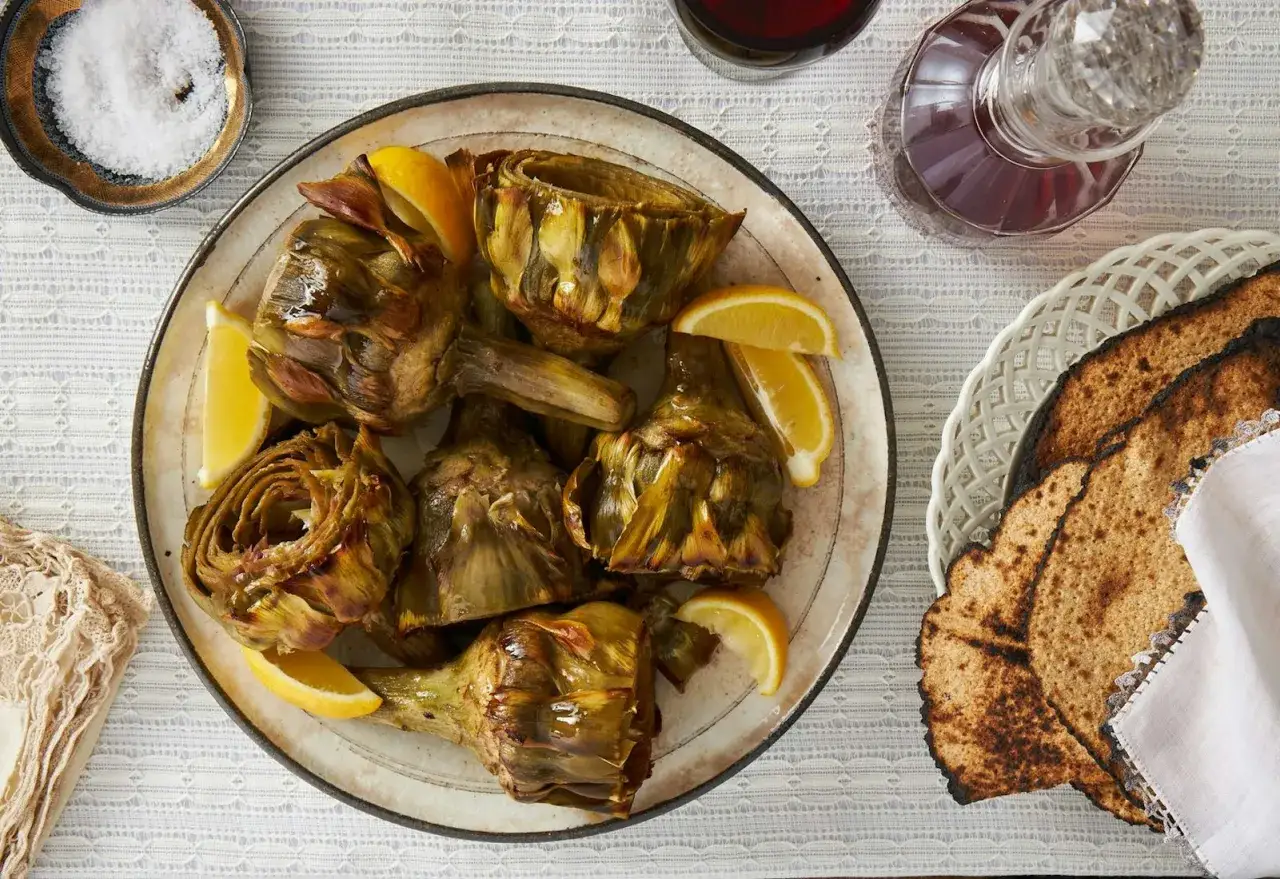 Artichauts à la romaine tendres et savoureux, servis avec des quartiers de citron. Une assiette qui invite à la dégustation.