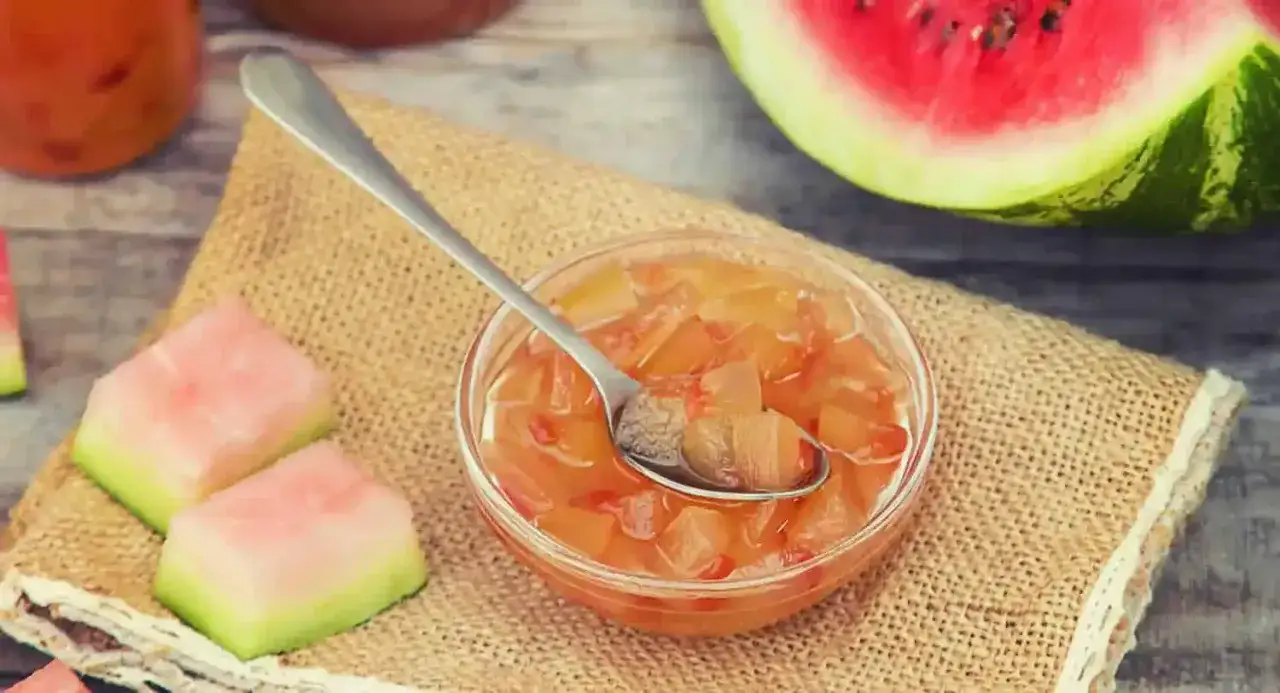 Un bol de past&egrave;que confite, avec des morceaux de past&egrave;que fra&icirc;che &agrave; c&ocirc;t&eacute;. Une cuill&egrave;re est plong&eacute;e dans la confiture.