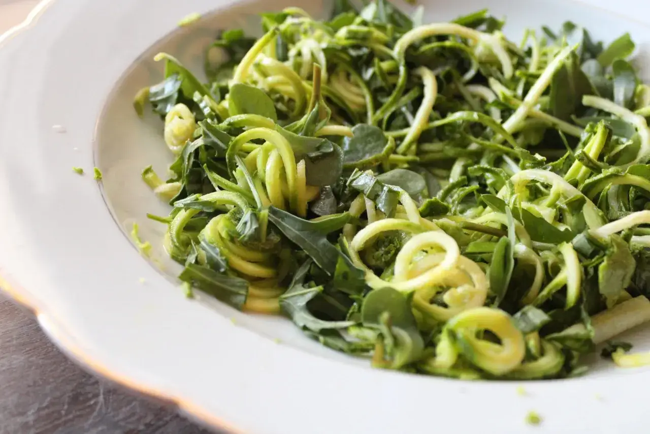 Salade fraîche de courgettes crues marinées au vinaigre, parsemée de feuilles vertes. Un délice croquant et acidulé.