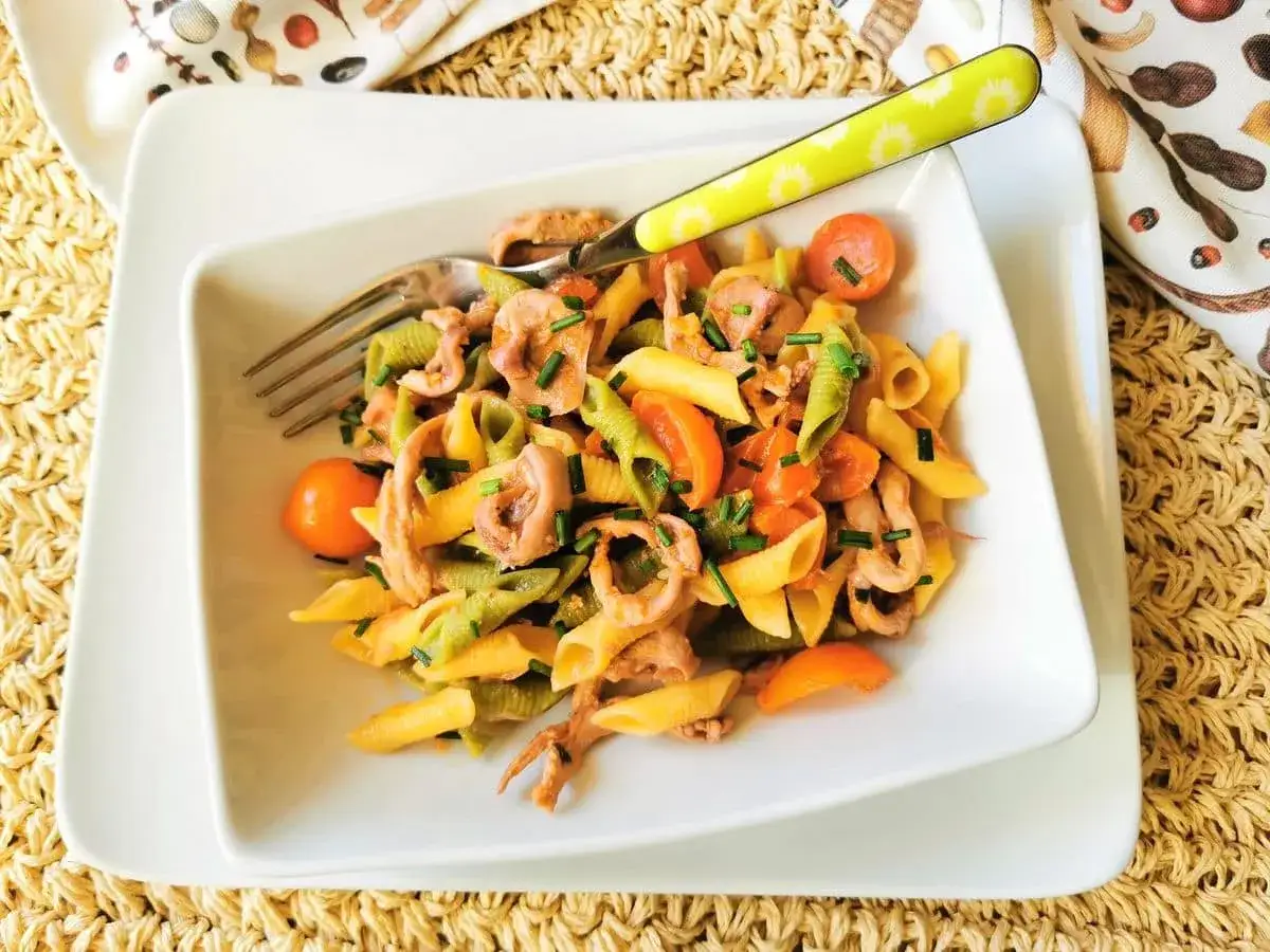 Assiette de p&acirc;tes aux calamars, tomates cerises et ciboulette. Un plat de p&acirc;tes aux calamars italiennes color&eacute;es et savoureuses.