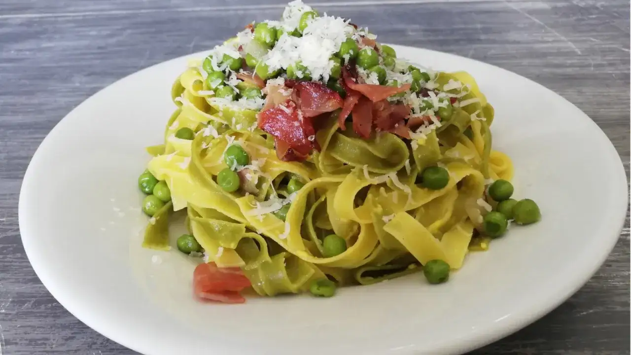 Fettuccine alla papalina, un plat de pâtes crémeuses avec des petits pois, du lard croustillant et du parmesan râpé.