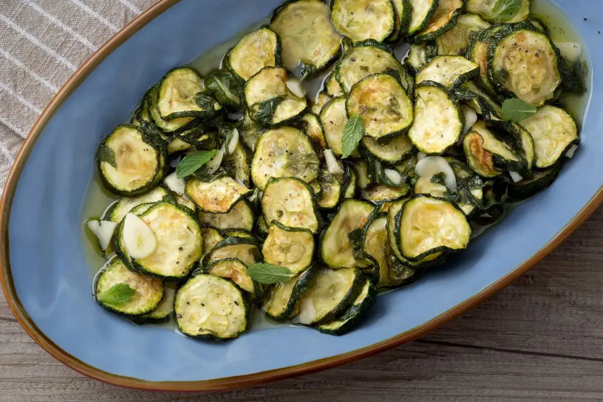 Zucchinis alla scapece, tranchés et marinés, baignent dans une sauce savoureuse avec de l'ail et de la menthe fraîche.