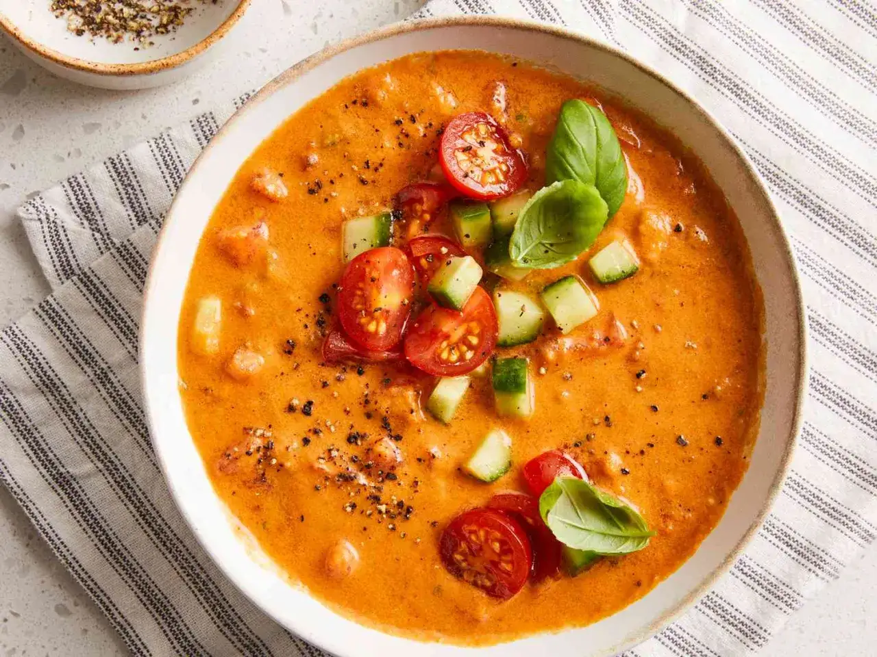 Un bol de gaspacho tomate, garni de d&eacute;s de concombre, de tomates cerises et de feuilles de basilic frais. Un d&eacute;lice rafra&icirc;chissant.