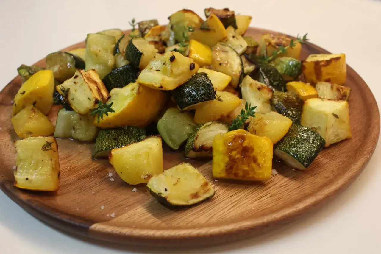 Assiette de courgette au four, coup&eacute;e en d&eacute;s et garnie de thym frais. Les l&eacute;gumes sont l&eacute;g&egrave;rement caram&eacute;lis&eacute;s, offrant une texture app&eacute;tissante.