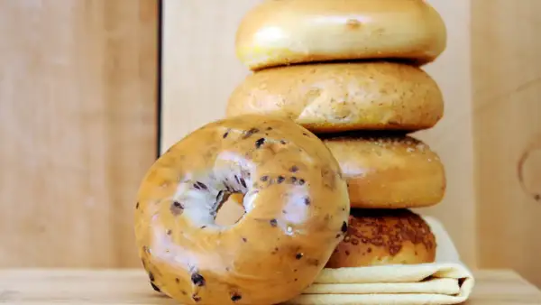 Pile de bagels, dont un aux myrtilles en premier plan. Parfait pour une recette bagel maison.
