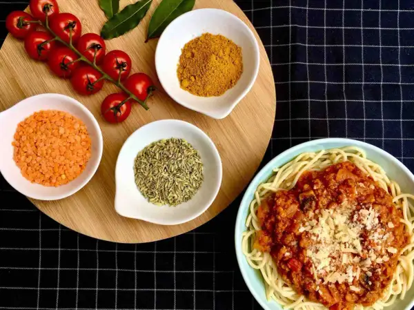Spaghetti al pomodoro avec lentilles corail, tomates cerises, curcuma et anis étoilé. Un plat savoureux et coloré.