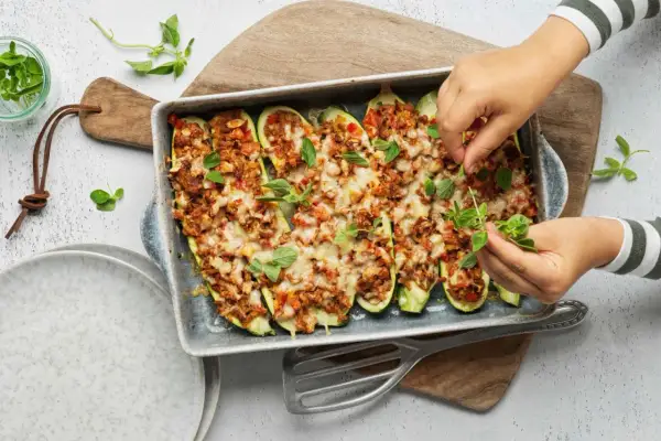 Courgettes farcies à la viande hachée, gratinées au fromage et garnies d'herbes fraîches. Une recette savoureuse prête à être dégustée.