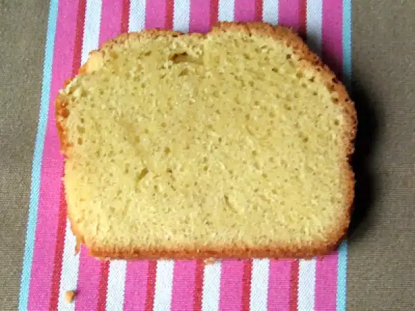 Une tranche de torta margherita, moelleuse et dorée, posée sur une serviette rayée rose et blanche.